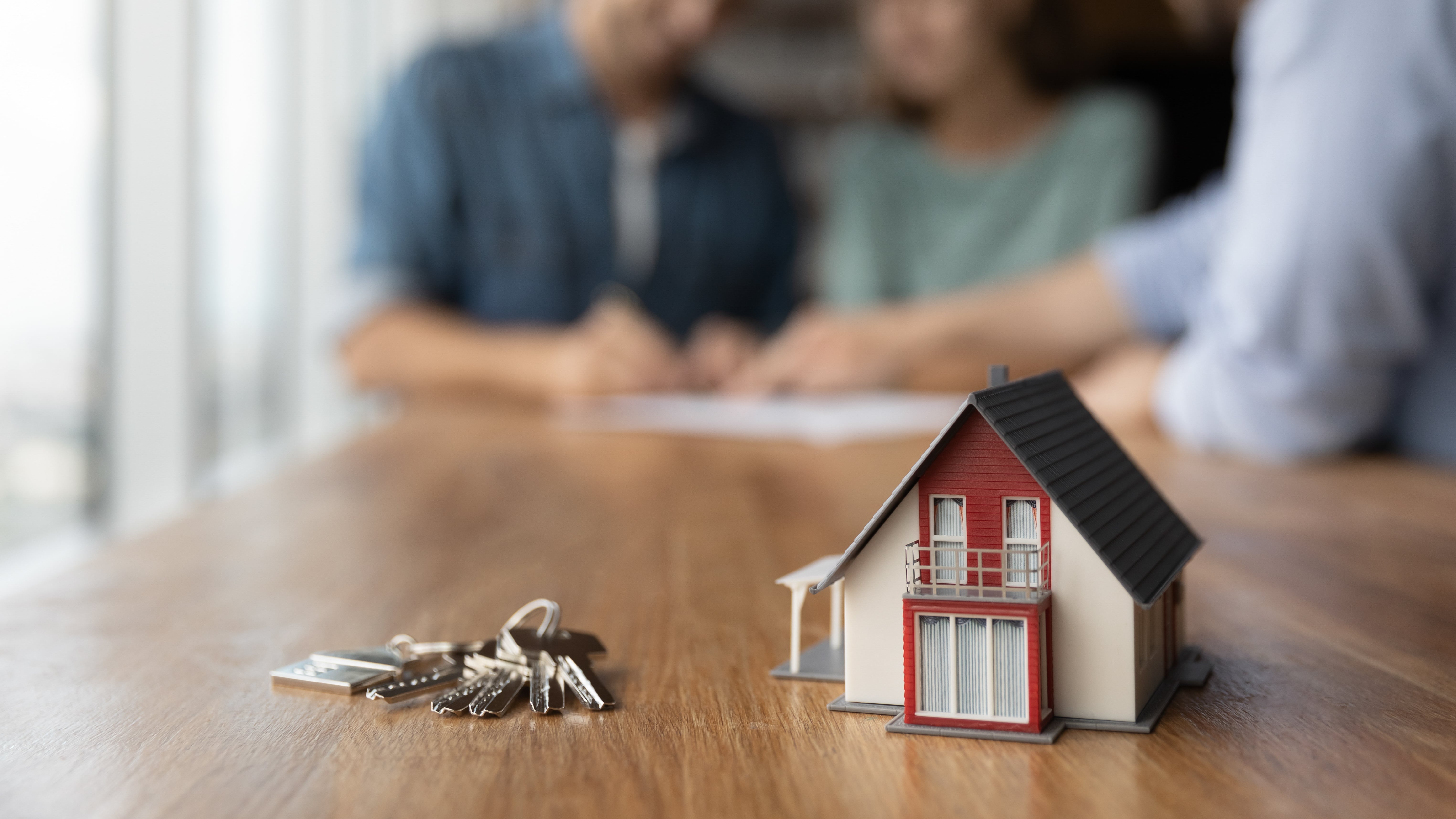 a key and miniature home on table with documents